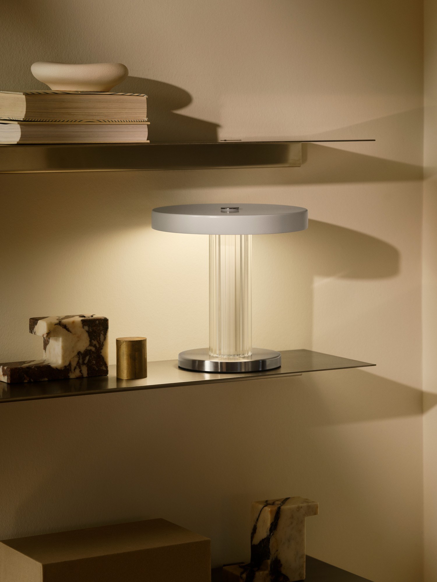 Lampe à poser sans fil Trezzi Portable en verre strié par Design For The People lampe à poser Trezzi Portable allumée sur une étagère