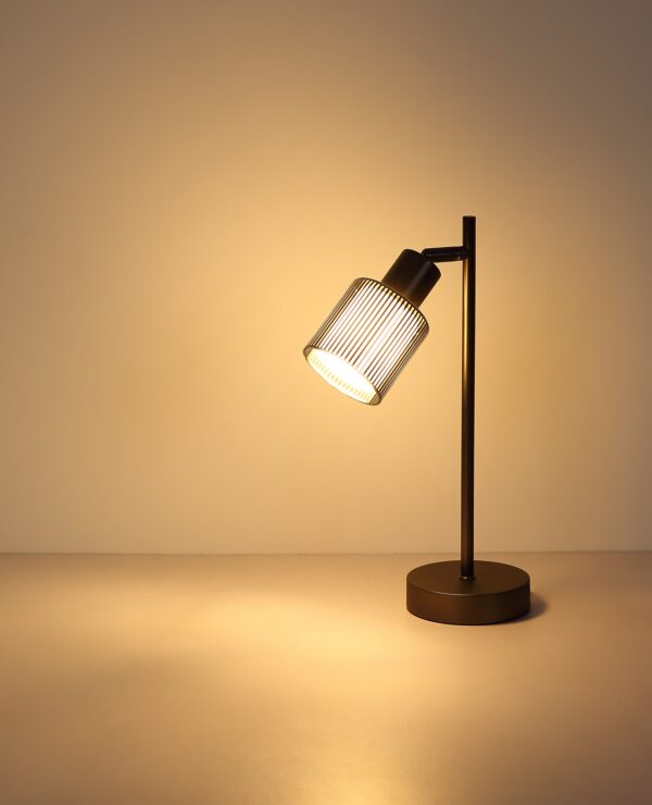 lampe à poser verre rayé gunmetal allumée, lumière chaude sur le mur