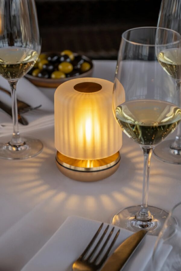 lampe rechargeable Firefly Humble, finition Gold Frosted sur une table de restaurant