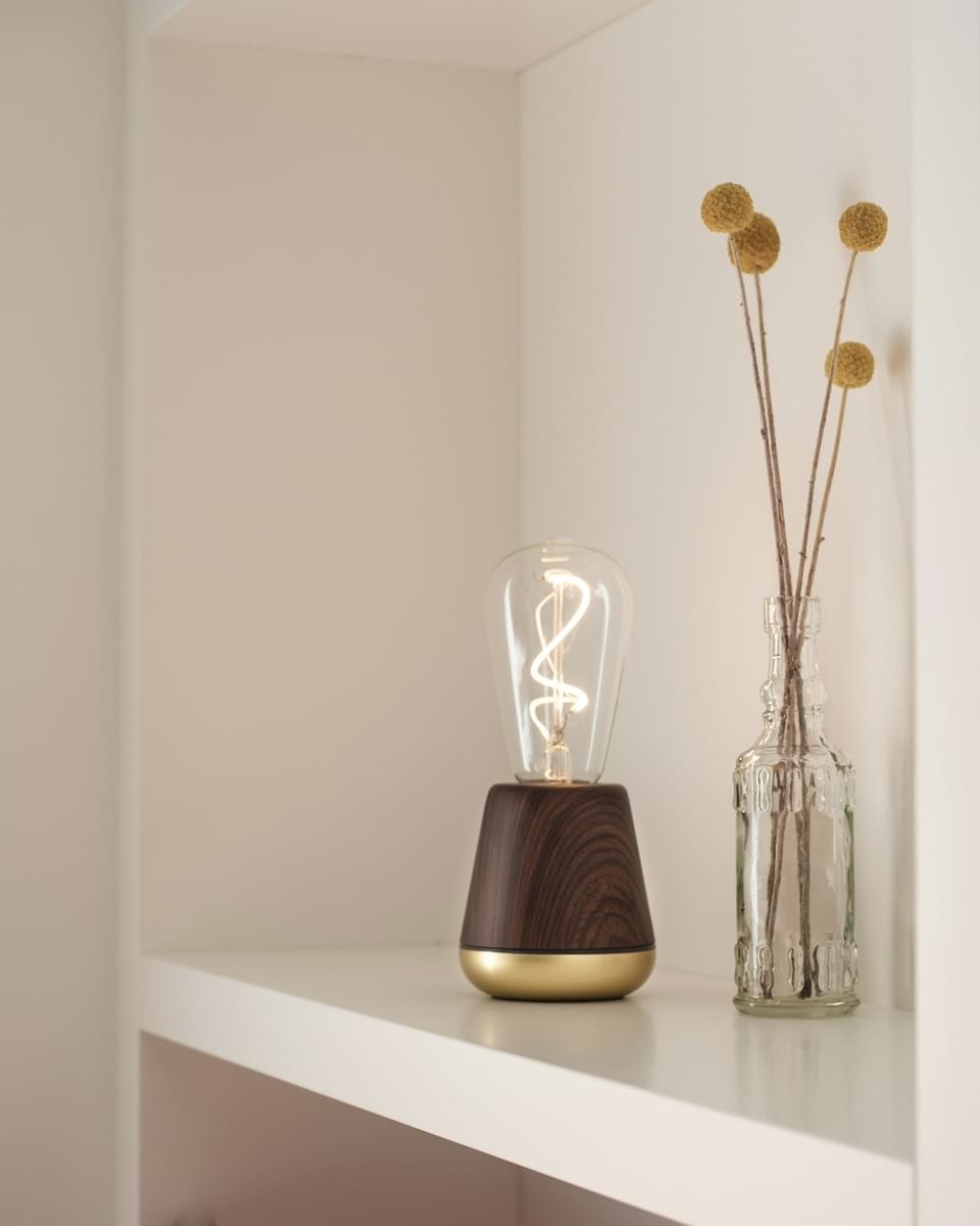 Lampe rechargeable One par Humble, ampoule à filament visible lampe rechargeable One Humble, finition Walnut sur une étagère