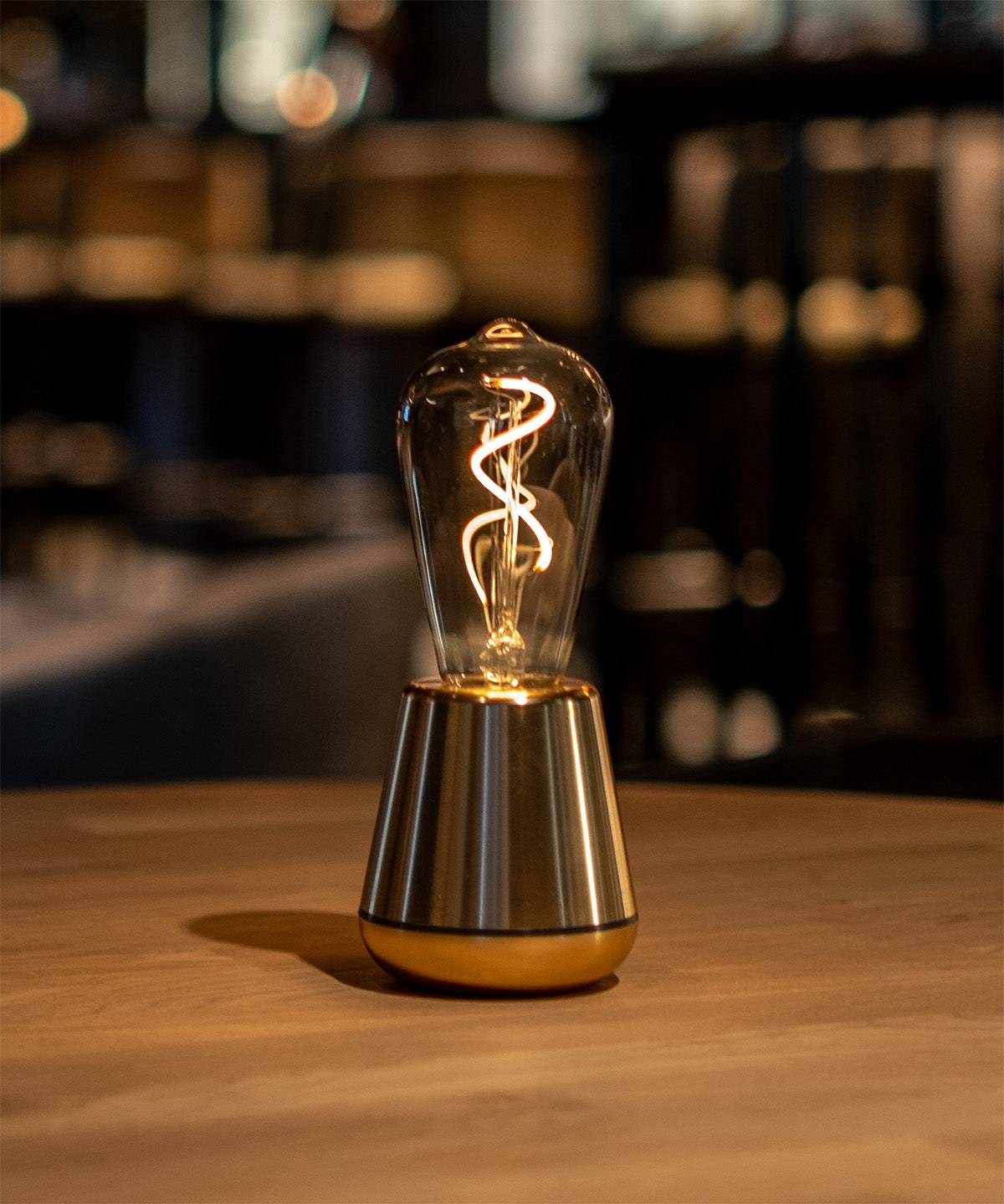 Lampe rechargeable One par Humble, ampoule à filament visible lampe rechargeable One Humble, finition Gold sur une étagère sombre