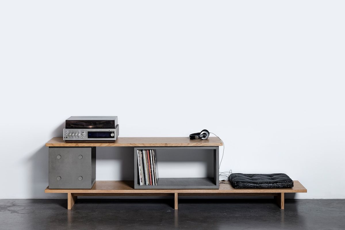 Meuble TV béton : comment bien le choisir pour son salon ? Meuble TV béton Dice Configuration 11 portant une platine vinyle et un casque, béton et chêne