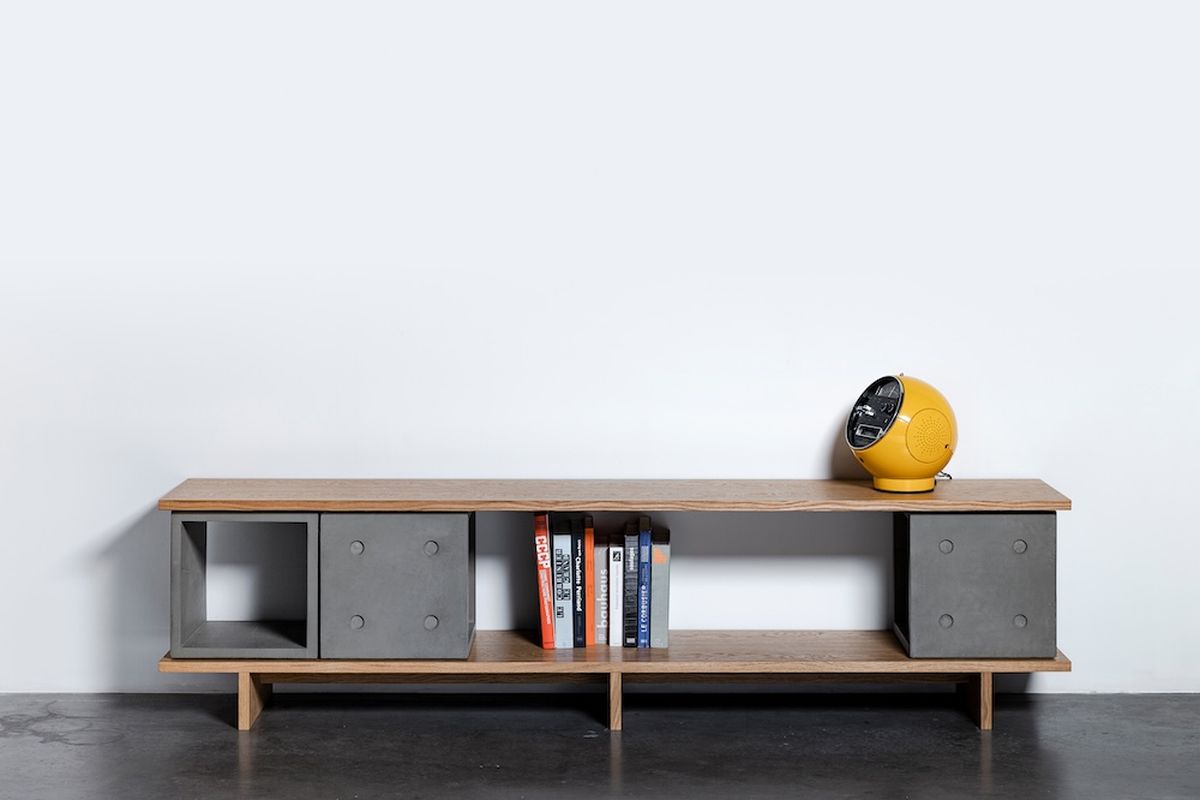 Meuble TV béton : comment bien le choisir pour son salon ? Meuble TV béton Dice Configuration 12 avec livres dans la niche et enceinte jaune sur le plateau