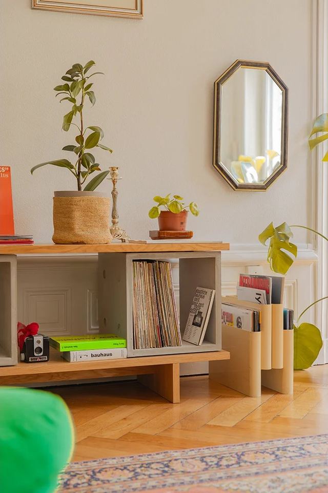 Meuble TV béton : comment bien le choisir pour son salon ? Meuble TV béton Dice dans un salon : niche en béton remplie de vinyles, plateau en chêne et plantes