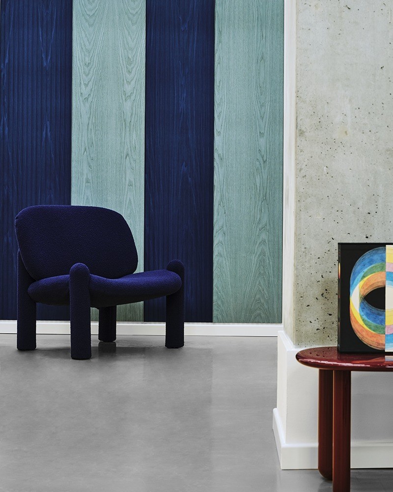 Panneau acoustique mural Woody par Slalom, placage de bois panneau acoustique bois Slalom Woody en bolivar bleu et vert au dessus d un fauteuil