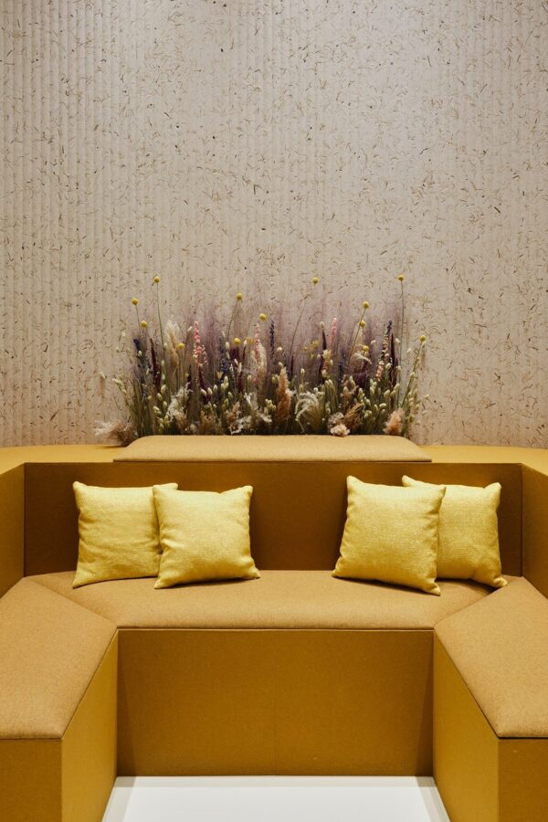 panneau acoustique herbes naturelles Slalom Grass derriere une banquette moutarde et des fleurs seches