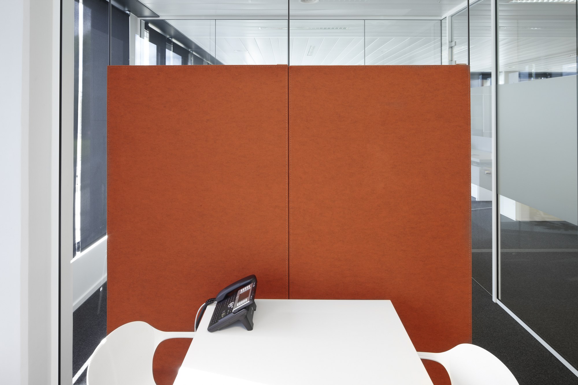 Panneau acoustique mural BuzziBack par BuzziSpace panneau acoustique mural BuzziBack orange derrière une table de travail blanche