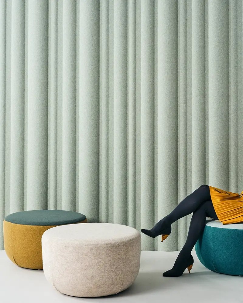 Panneau acoustique ondulé ECOrange Wave par Slalom, effet drapé panneau acoustique ondulé Slalom ECOrange Wave vert derriere des poufs