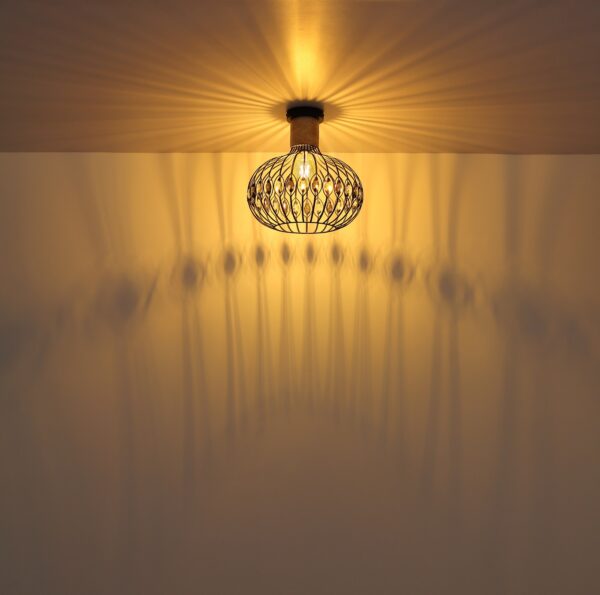 Lampe travertin : luminaires en travertin plafonnier travertin noir allumé, lumière chaude et ombres de la cage sur le plafond