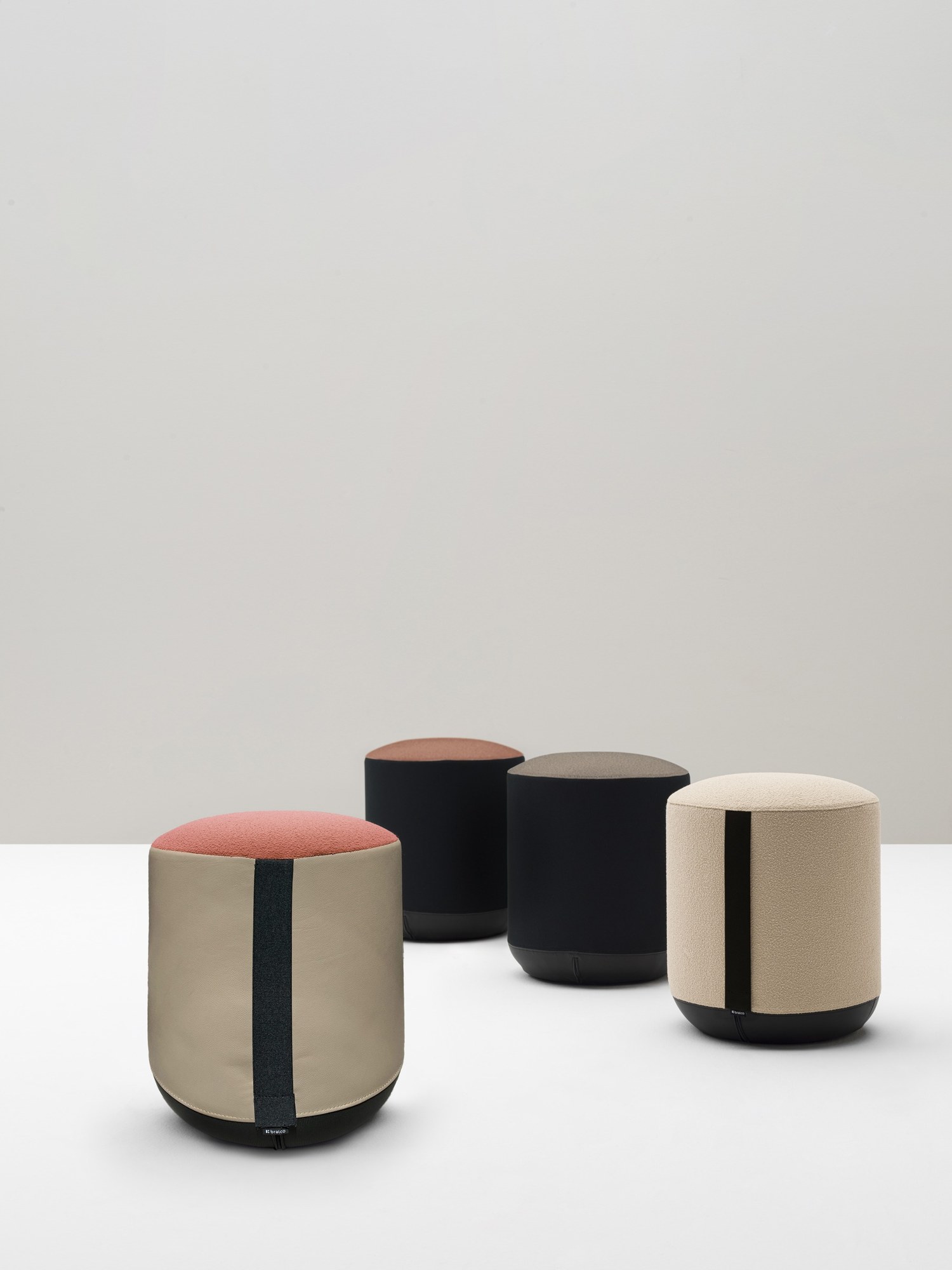 Pouf de bureau Bi par Bralco, 4 formes, bicolore ou bi-matière quatre poufs ronds Bi Bralco bicolores en tissu beige, noir et corail, ambiance de studio