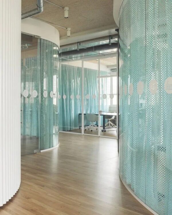 rideau acoustique Slalom Curtain bleu perfore devant une cloison vitree de bureau