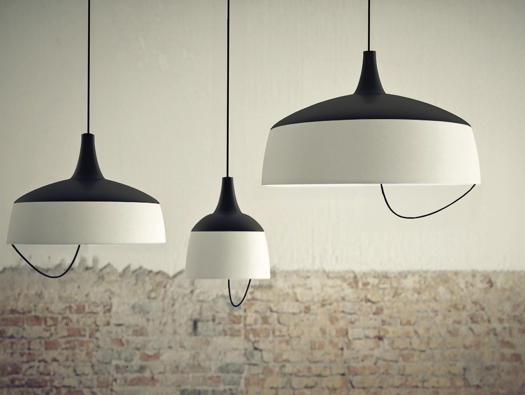 Suspension Barna en aluminium par Robin Lamps suspension Barna trois suspensions noir et blanc mat de deux tailles, vue large devant un mur de briques