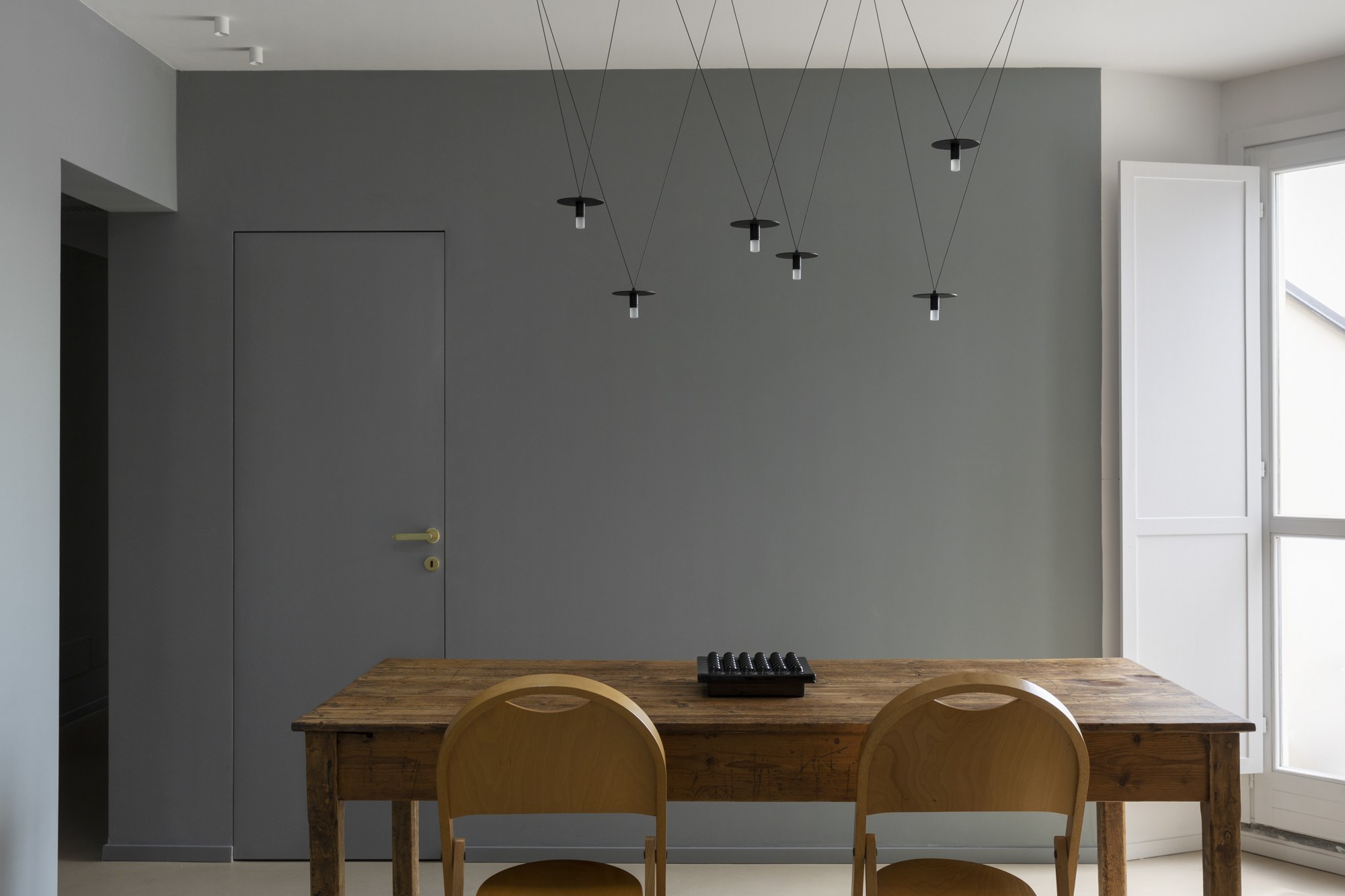 Suspension D02 Pendant par OliveLab, 4, 6 ou 8 points lumineux suspension D02 Pendant OliveLab, finition noir mat au-dessus d'une table en bois