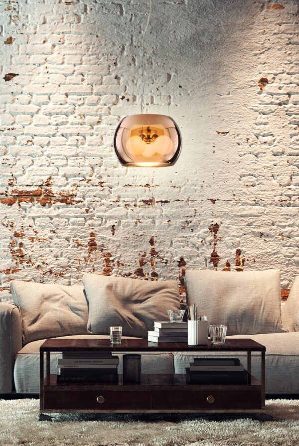 suspension globe verre cuivré dans un salon devant un mur en brique