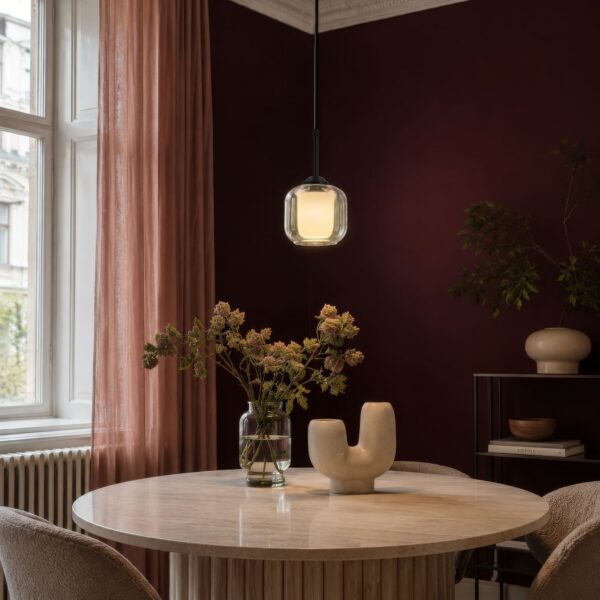 suspension globe verre dépoli au dessus d une table ronde en travertin