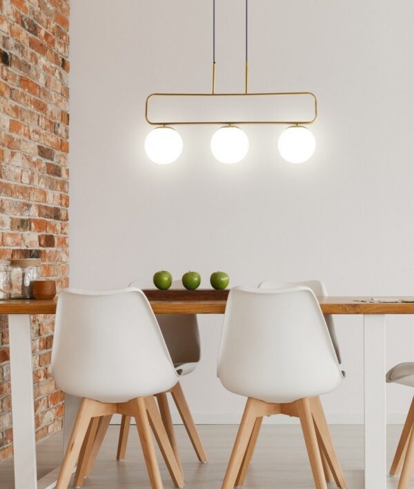suspension laiton globes blancs au dessus d une table à manger devant un mur de briques