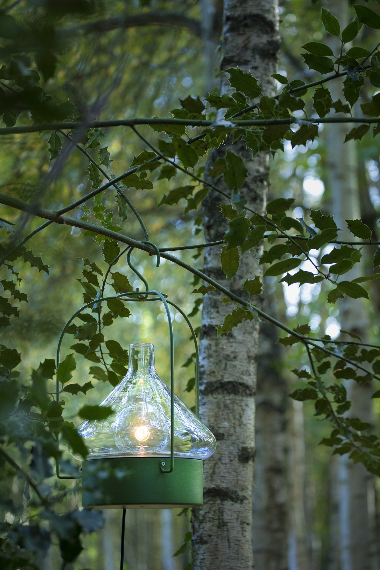 Suspension nomade La Hutte par Roger Pradier, verre soufflé suspension nomade La Hutte teinte vert fougère suspendue entre des bouleaux