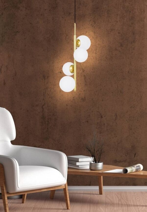 suspension quatre globes laiton laiton pres d un fauteuil blanc sur un mur brun