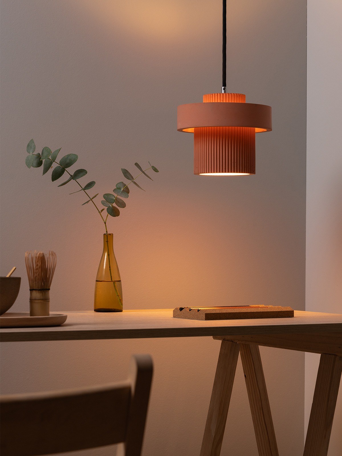 Suspension S9 en béton up and down par Stefan Gant x Gant Lights Suspension S9 en béton corail allumée au-dessus d'une table