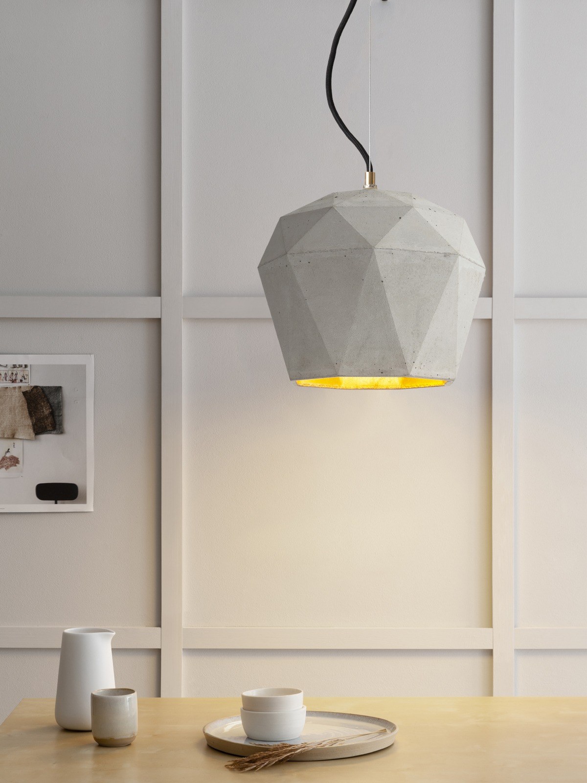 Suspension T4 béton clair allumée au-dessus d'une table, intérieur doré