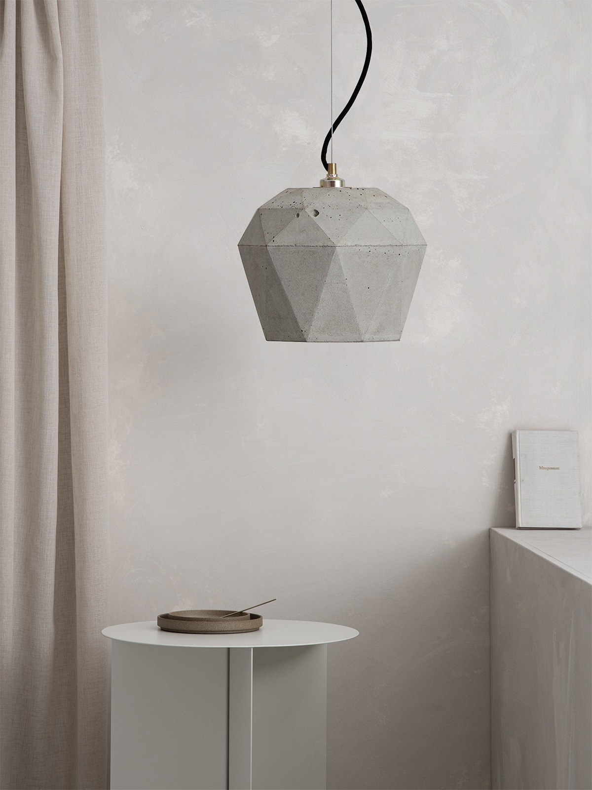 Suspension T4 béton clair triangulaire par Stefan Gant x Gant Lights Suspension T4 béton clair suspendue au-dessus d'une table de chevet