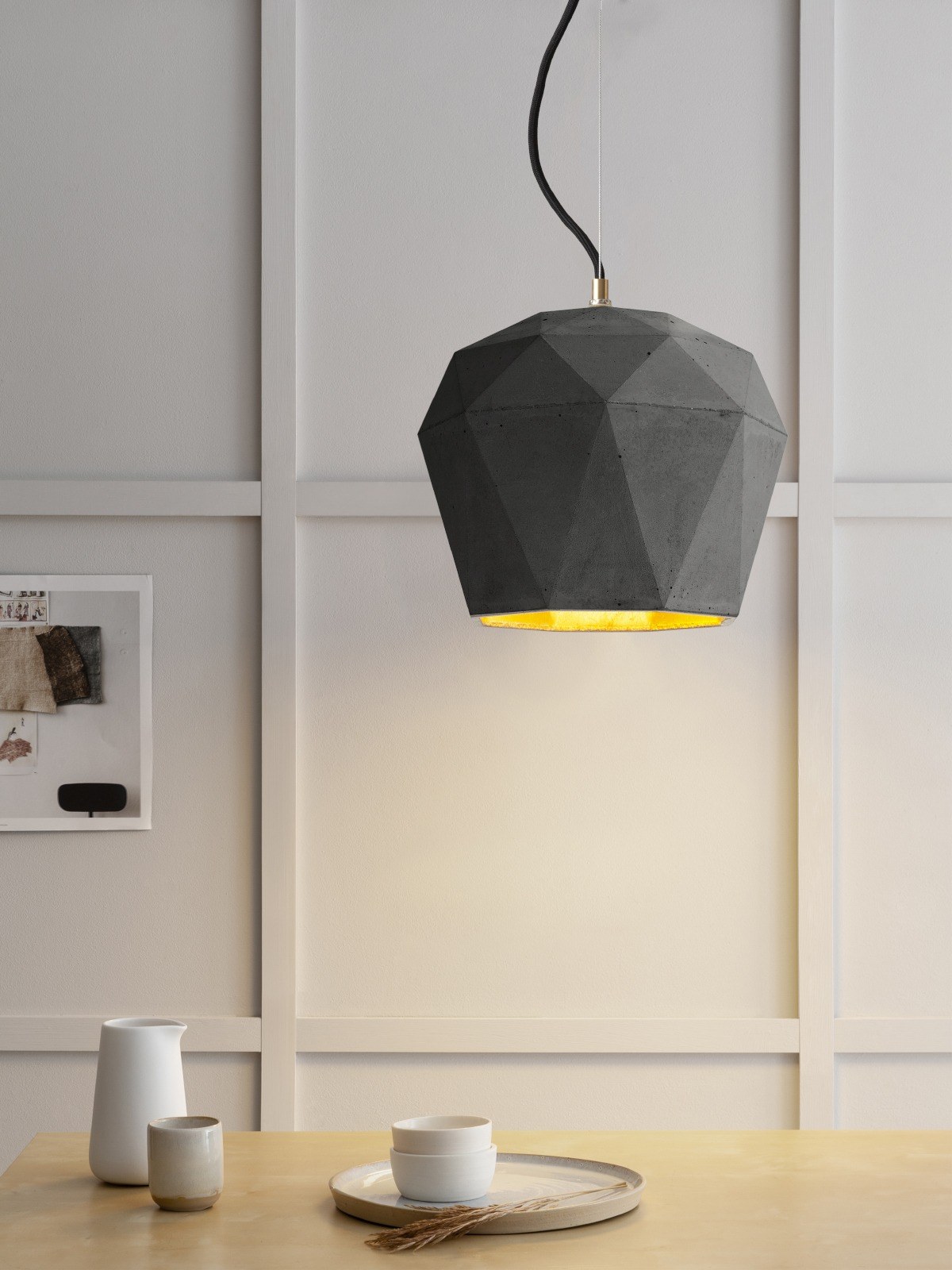 Suspension T4 béton foncé allumée au-dessus d'une table, intérieur doré