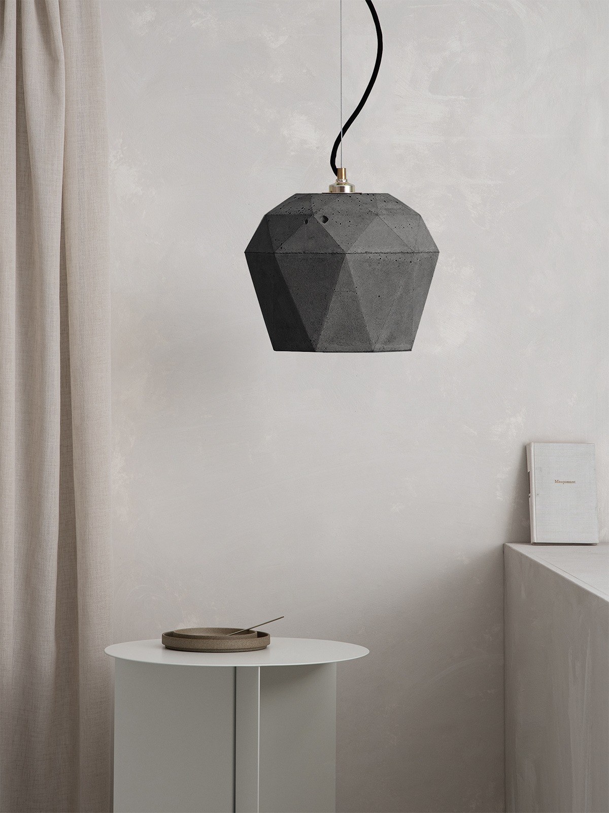 Suspension T4 béton foncé triangulaire par Stefan Gant x Gant Lights Suspension T4 béton foncé suspendue au-dessus d'une table de chevet
