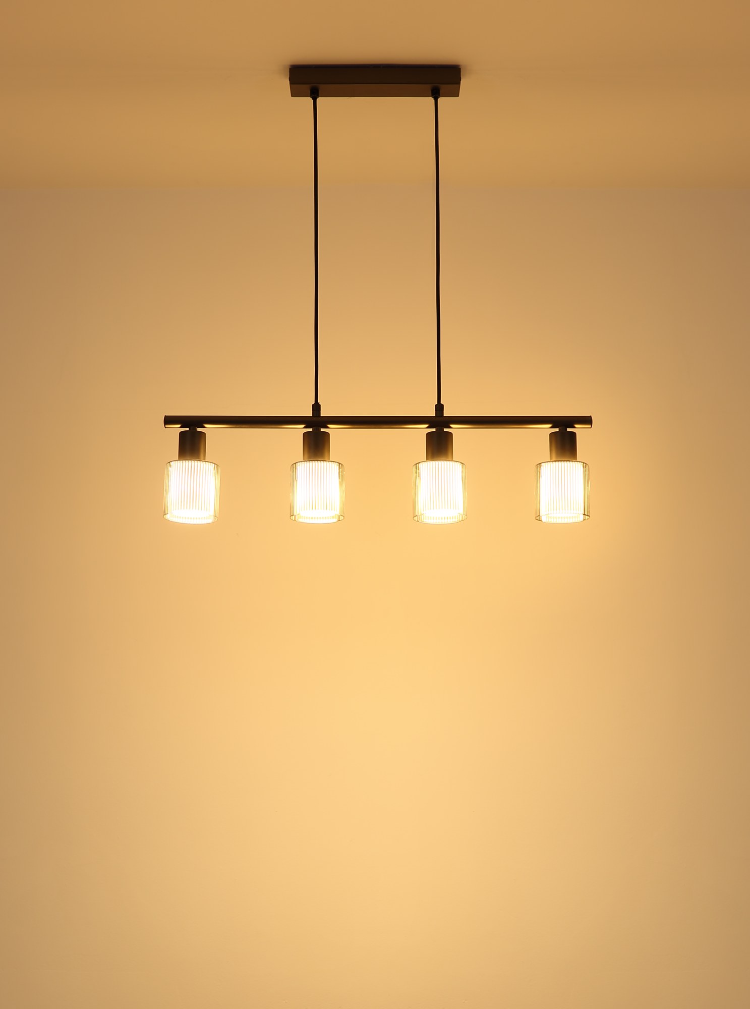 Suspension verre rayé gunmetal, 4 lumières E14 sur barre suspension verre rayé gunmetal allumée, lumière chaude sur le mur