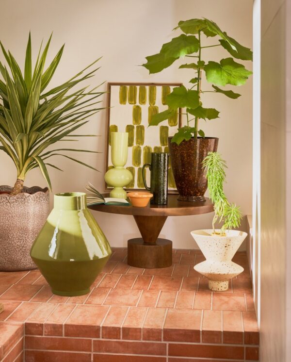table basse manguier Spiss Urban Nature Culture, dans un coin avec des plantes et des vases sur un sol en briques