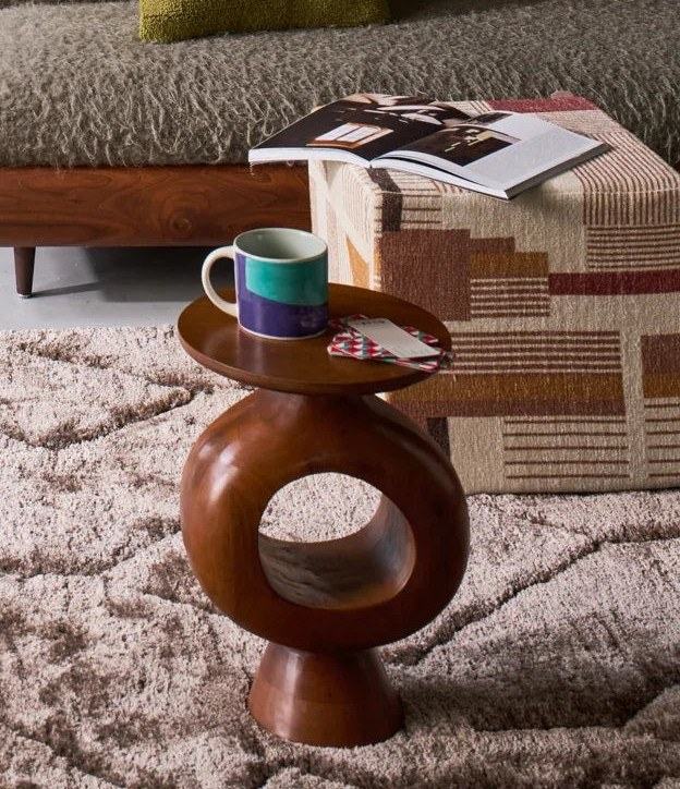Table d'appoint bois : laquelle choisir pour votre salon ? Table d'appoint bois Farren en manguier, plateau avec mug et livre près d'un canapé sur un tapis