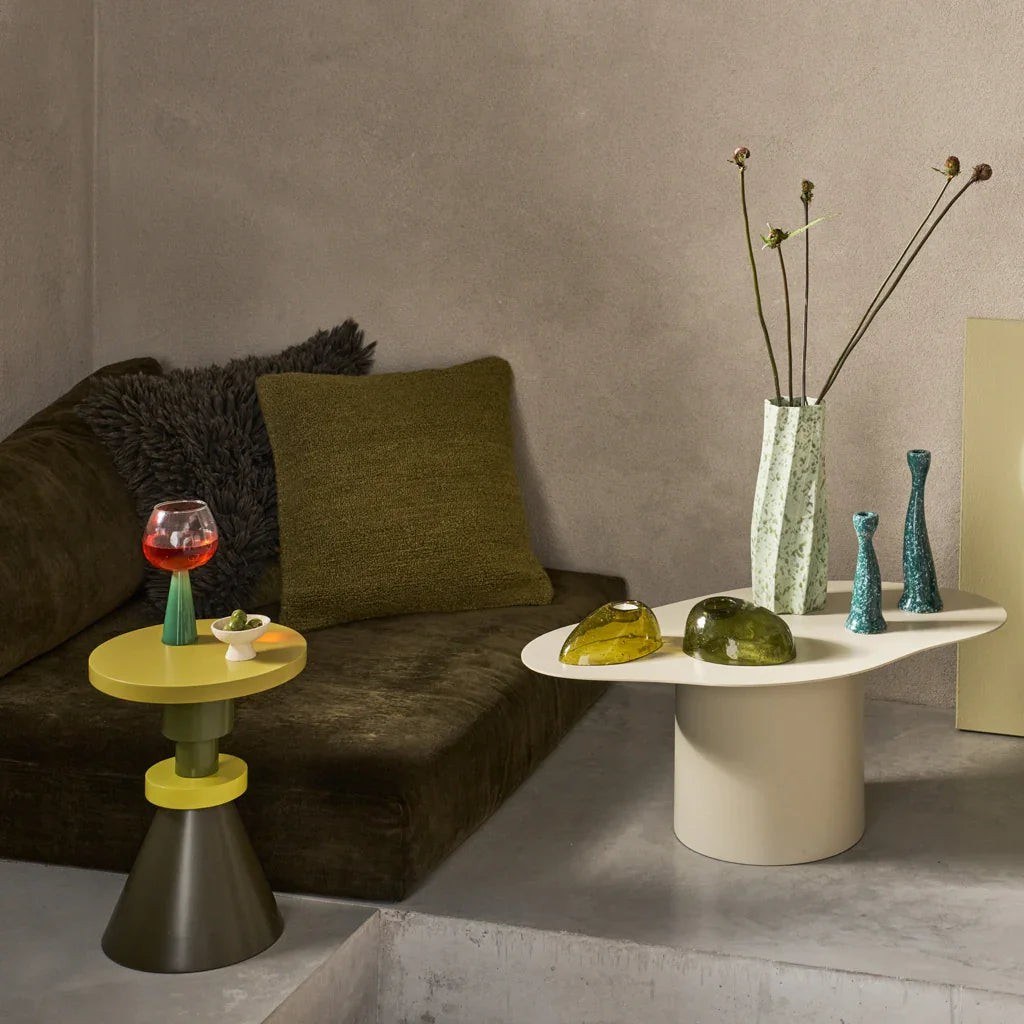 Table d'appoint Gjeng par Urban Nature Culture, manguier vert et jaune table d'appoint bois Gjeng Urban Nature Culture, près d'un banc en velours vert avec des vases en céramique