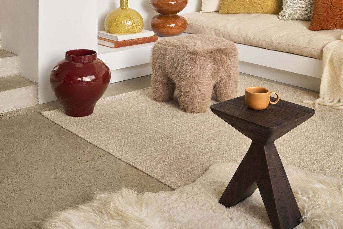 Table d'appoint bois : laquelle choisir pour votre salon ? Table d'appoint bois Sion en manguier teinté noyer, avec une tasse, posée sur un tapis dans un salon