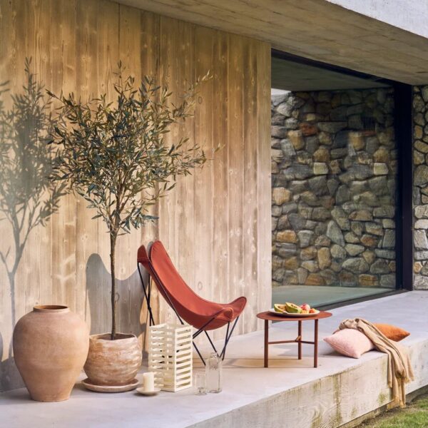 table d'extérieur Tiago Urban Nature Culture, sur une terrasse près d'un fauteuil papillon et d'une poterie