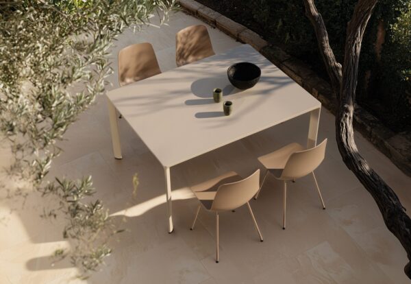 table terrasse Inclass Laminar Outdoor beige avec quatre chaises sur un dallage sous un olivier