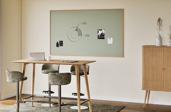 tableau blanc cadre bois Sharp Oak Chameleon accroché au-dessus d'une table haute en chêne