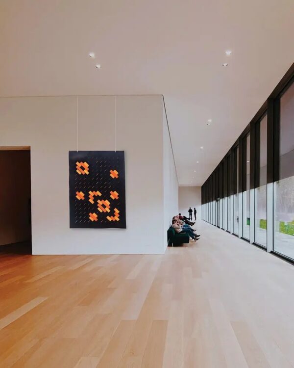 tenture acoustique Slalom Trama Ordito noire et orange accrochee dans une galerie lumineuse