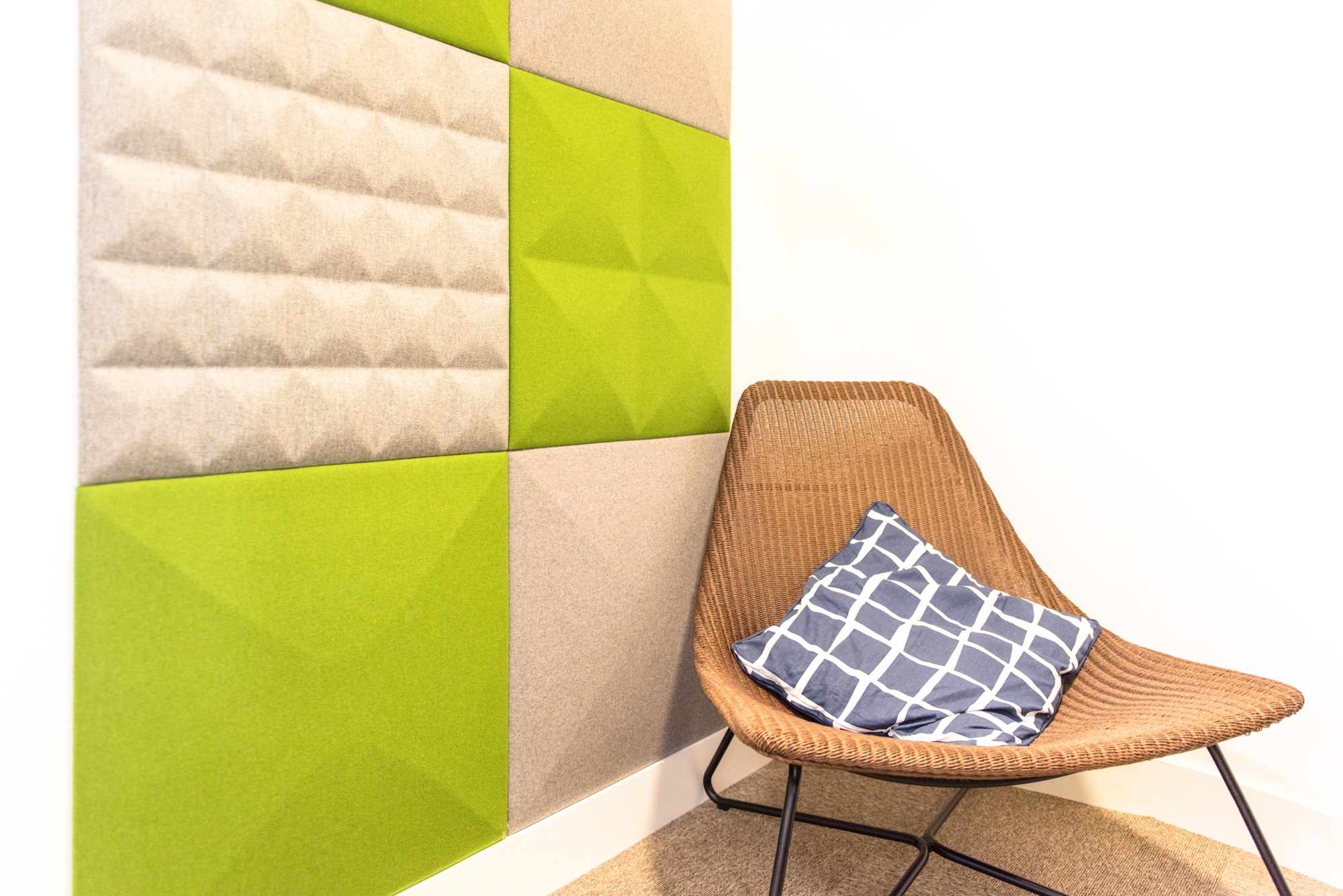 Tuile murale acoustique BuzziTile 3D par BuzziSpace tuile murale acoustique BuzziTile 3D, détail des motifs en relief vert et beige à côté d un fauteuil