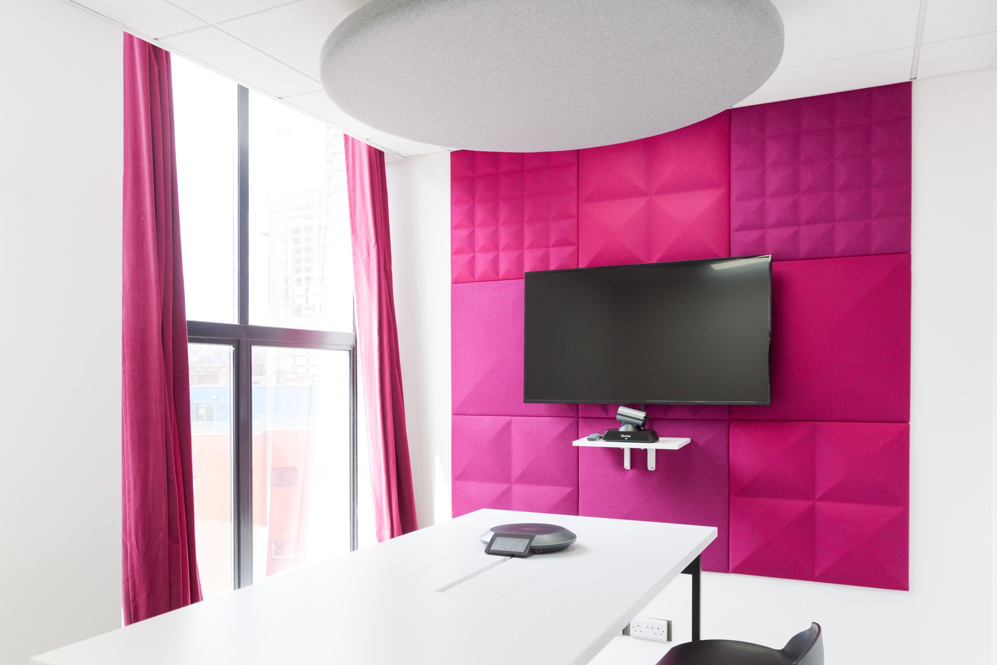 Tuile murale acoustique BuzziTile 3D par BuzziSpace tuile murale acoustique BuzziTile 3D rose derrière un écran de visioconférence