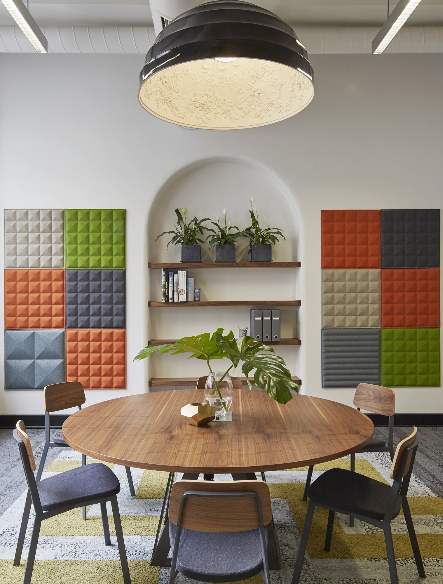 Tuile murale acoustique BuzziTile 3D par BuzziSpace tuile murale acoustique BuzziTile 3D multicolore de chaque côté d une niche, autour d une table ronde