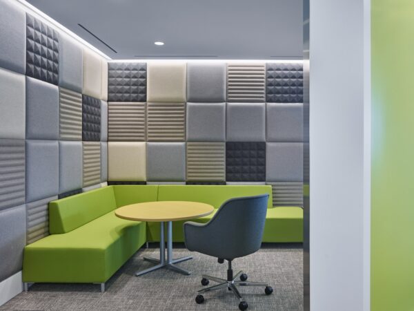 tuile murale acoustique BuzziTile Flat, tuiles lisses et à motifs grises et beiges derrière une banquette verte
