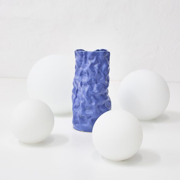 vase céramique Wrinkled blue posé près de globes blancs