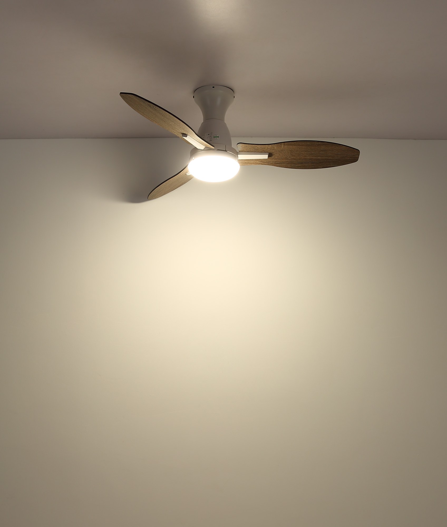Ventilateur de plafond avec lumière LED et pales décor bois, Ø 107 cm ventilateur plafond 107 cm à trois pales décor bois foncé avec lumière LED, corps blanc allumé au plafond, lumière LED chaude